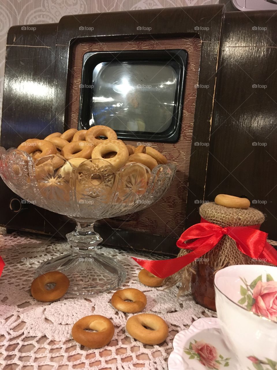 The vintage kitchen decoration. Old TV set, bagels, a jam jar and tea cup. Vintage background. 