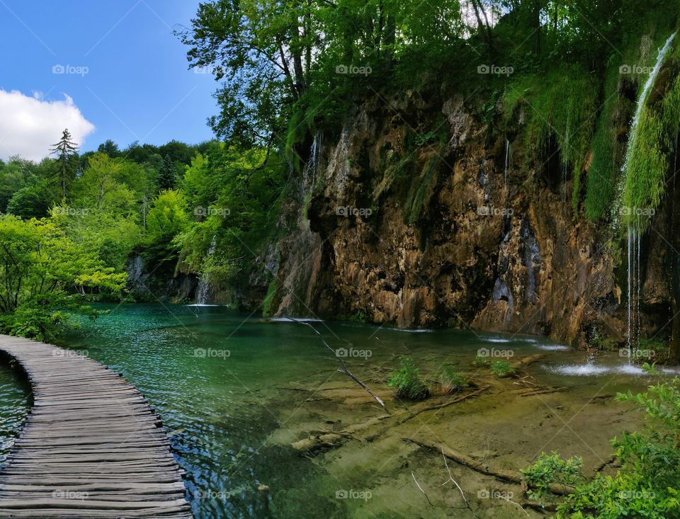Wooden bridge across the turquoise lake in the waterfall