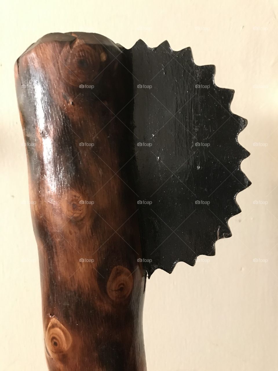 A razored saw blade repurposed as an axe head. This painted metal piece was permanently affixed to a varnished tree branch which functions as a weapon handle. What a creative way to construct an axe from old items found around the house.