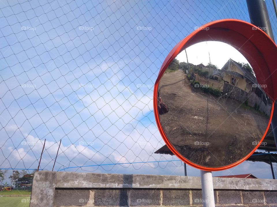 road sign mirrors under clear skies and warm sunlight, installed on road corners as a driving safety device.