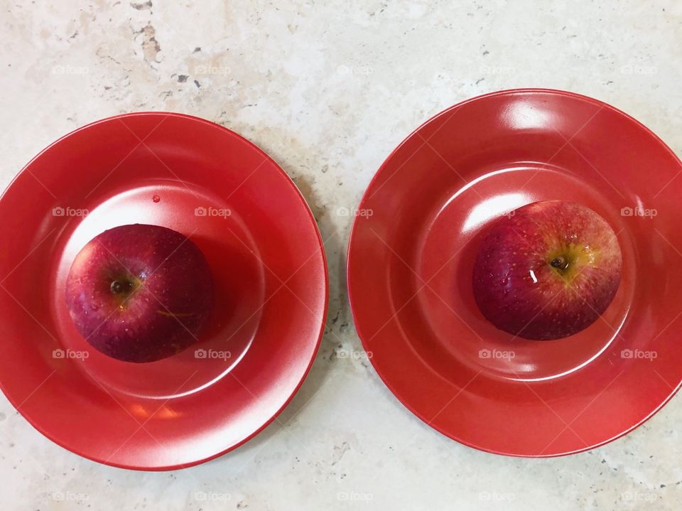 Two red apples on the red plate