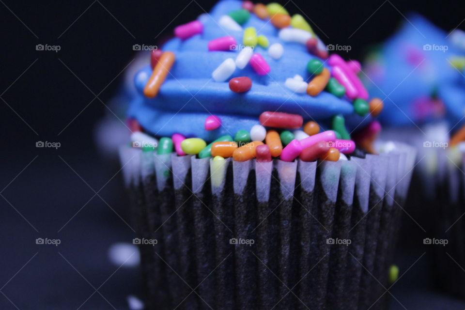 Chocolate cupcakes with blue frosting and multicolored sprinkles