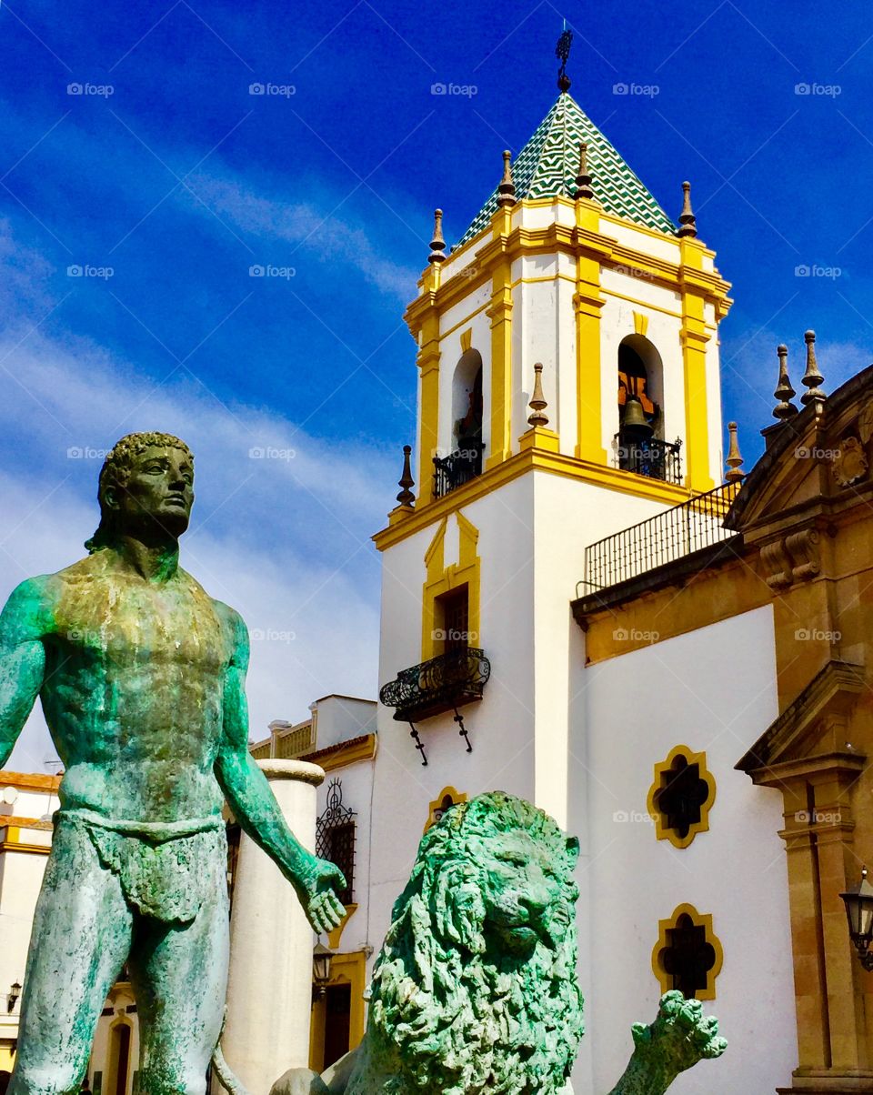 Plaza in Ronda Spain with bell tower and bronze statue of man and lion