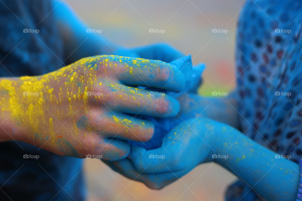 Holi paints festival. Hands holding holi paints close up. Hands in blue and yellow paint