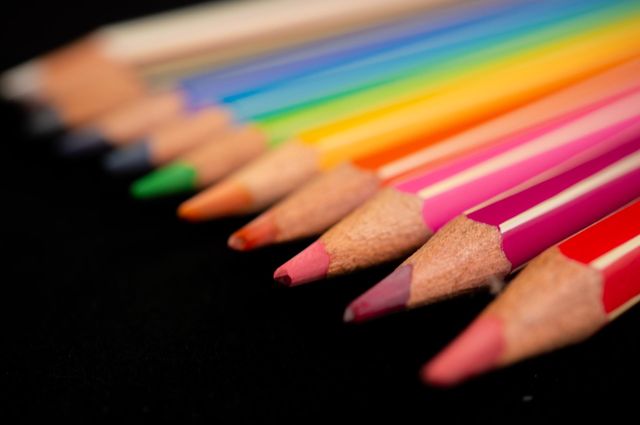 Colored pencils in a row with a black background