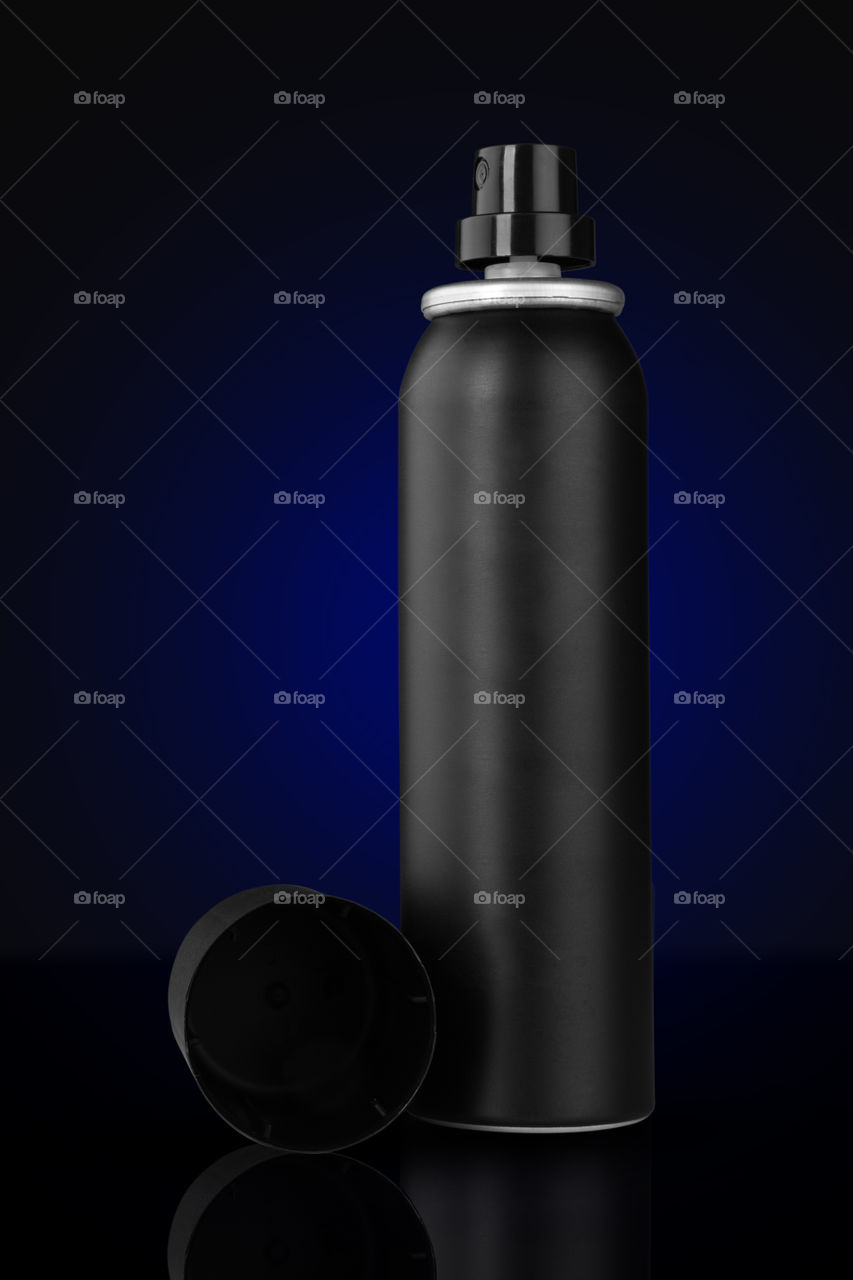 Black deodorant perfume spray can on blue background