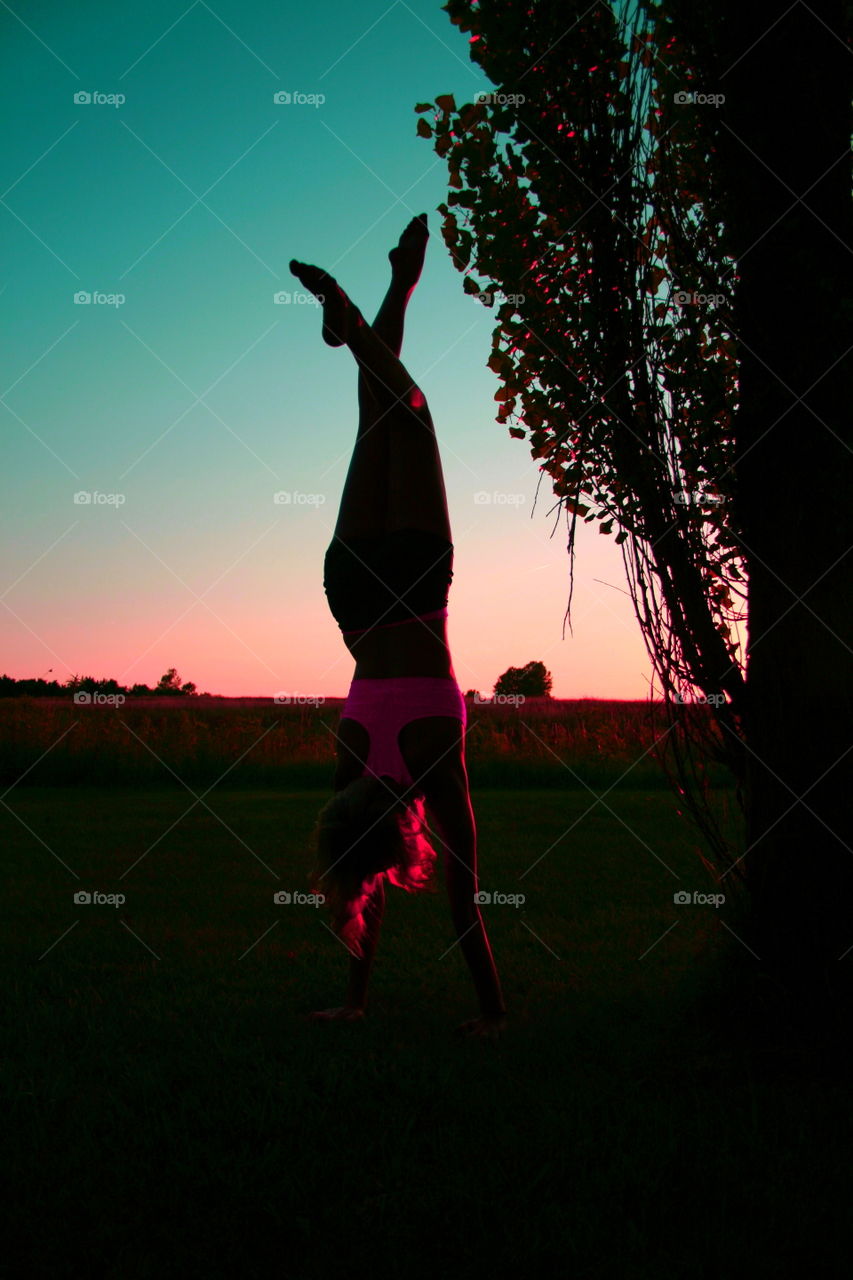 Woman doing handstand exercise during sunrise