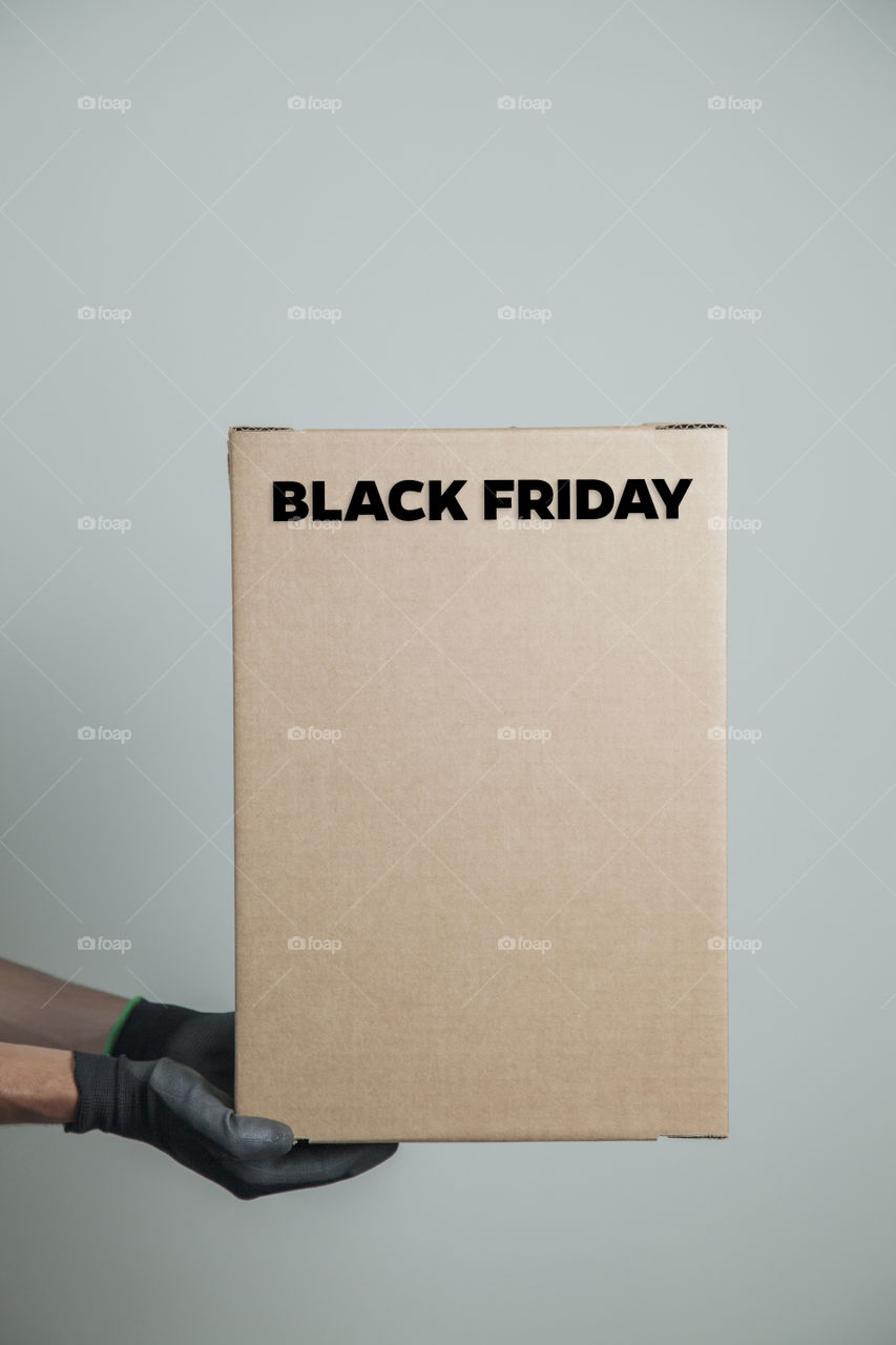 Cardboard box with black friday order written on the box placed on the floor in an empty room with a neutral background. delivery concept. economy concept. black friday concept. shopping concept.