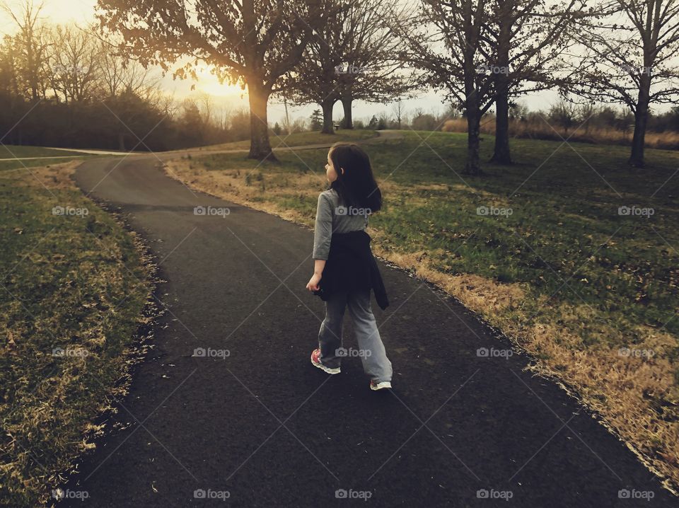 Little girl on a quiet walk in the park at sunset 