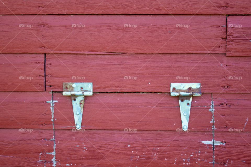 Isolated view of hinges on the siding of a red barn 