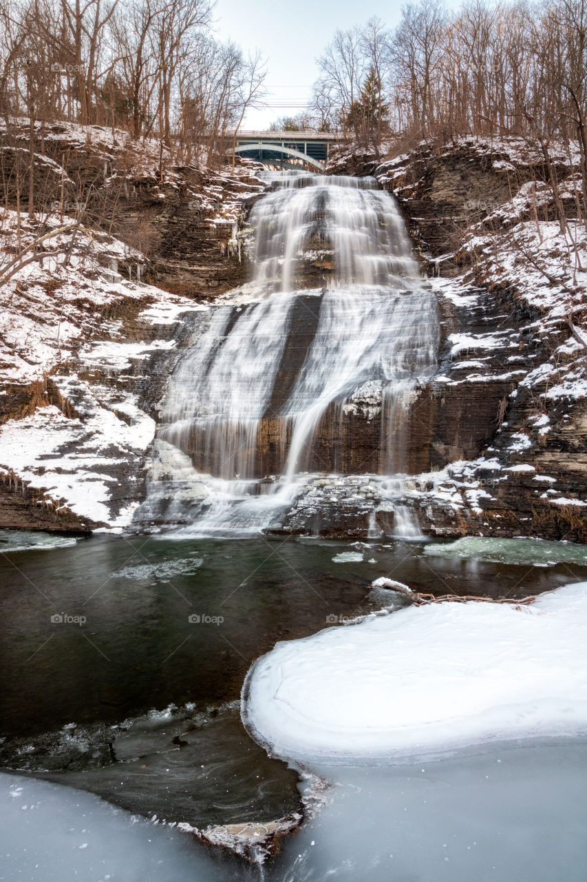 Snow covered waterfall with ice surrounding a small lake. Winter wonderland scene