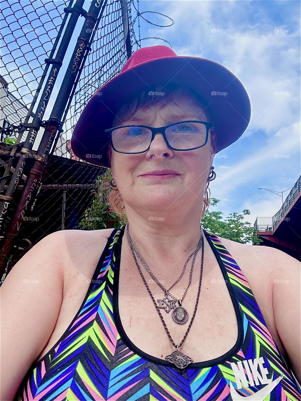 This is me, “Petra Schiller” a.k.a. “Maxine Firefox” wearing my favorite burgundy Fedora standing in the parking lot beneath the “Pulaski Bridge” at “Newtown Creek” in LIC, Queens. 2024. Hypnotic Productions