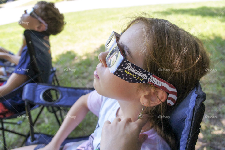 Side view of a girl and boy looking at eclipse