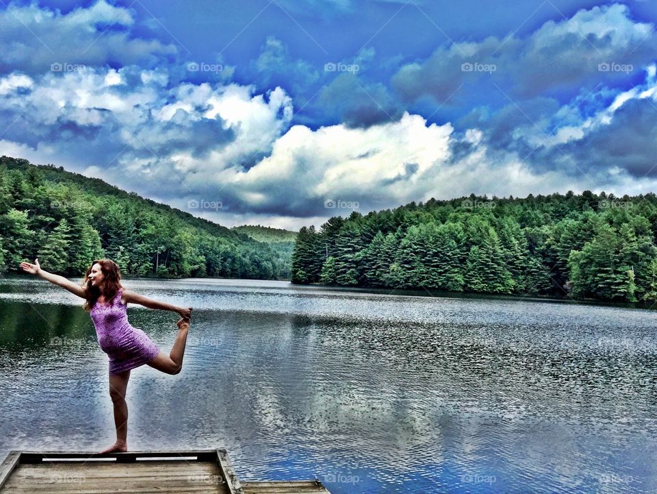 Woman doing yoga on pier near river