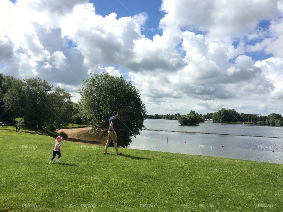 Father and daughter running towards beach, Cotswolds, UK
