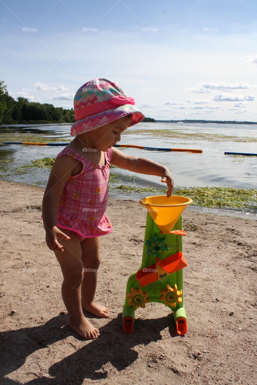 Toddler girl playing plastic toy at lakeshore