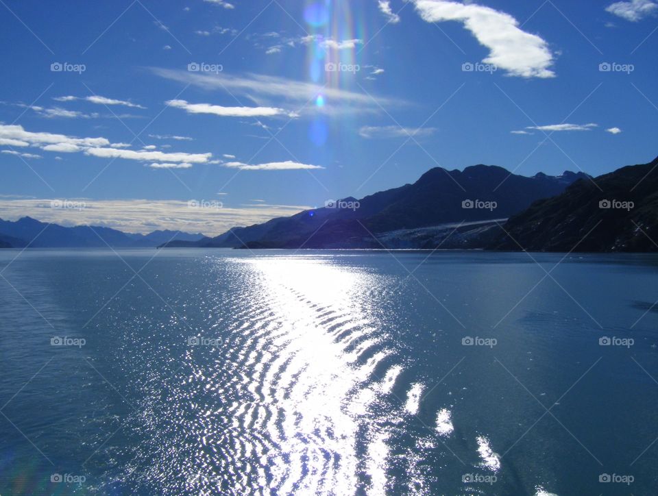 Bright sunny day view of ocean and mountains traveling through inside passage on cruise ship in Alaska