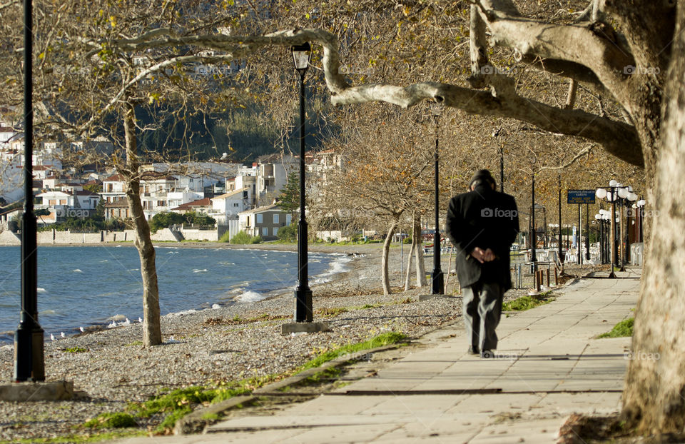 old man walking on Beach road in Nafpaktos, Gulf of Corinth, in fall