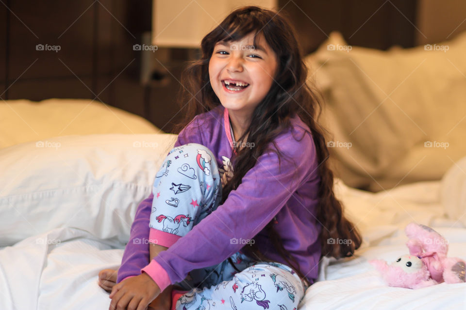 Laughing cute little girl in pajamas with unicorns and rainbows