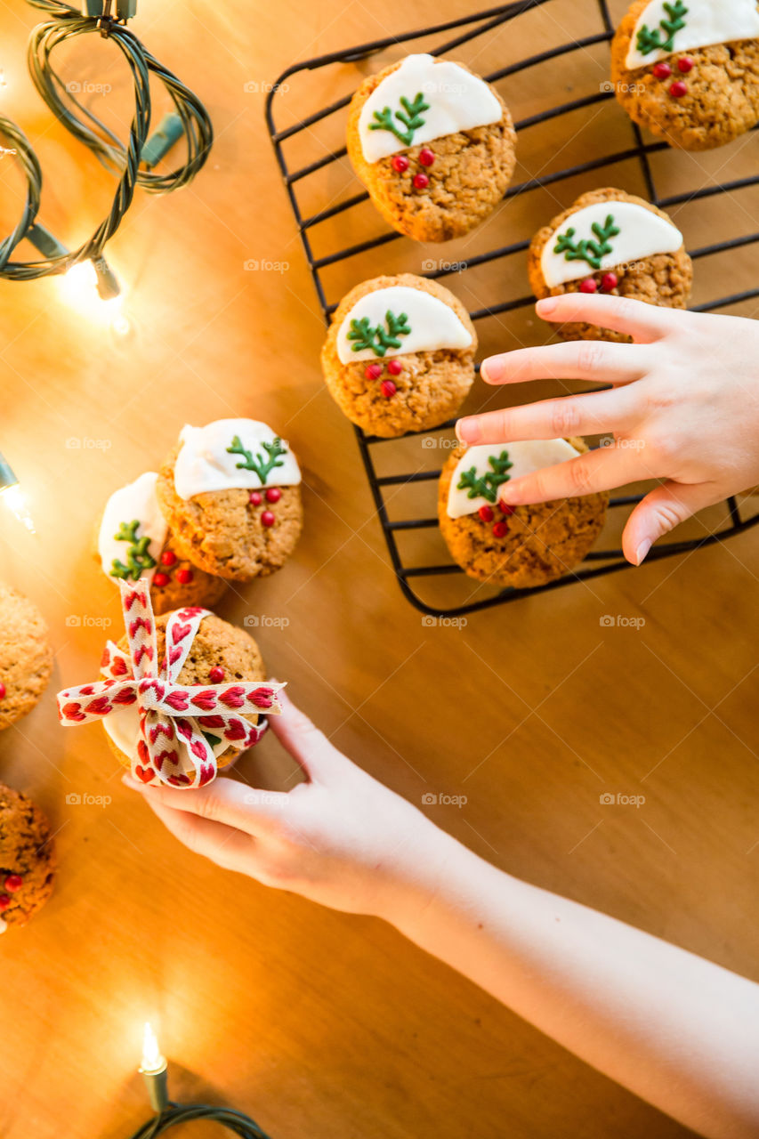 Handmade Christmas cookies make the best gifts! Image of girl's hands at biscuits with fairy lights.