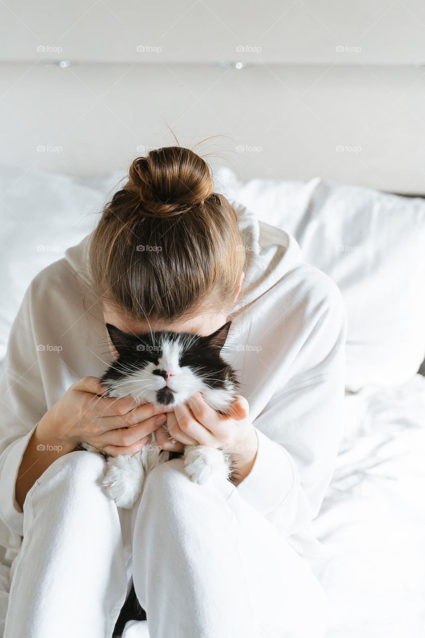 Unrecognizable woman cuddling with white black fluffy cat pet 