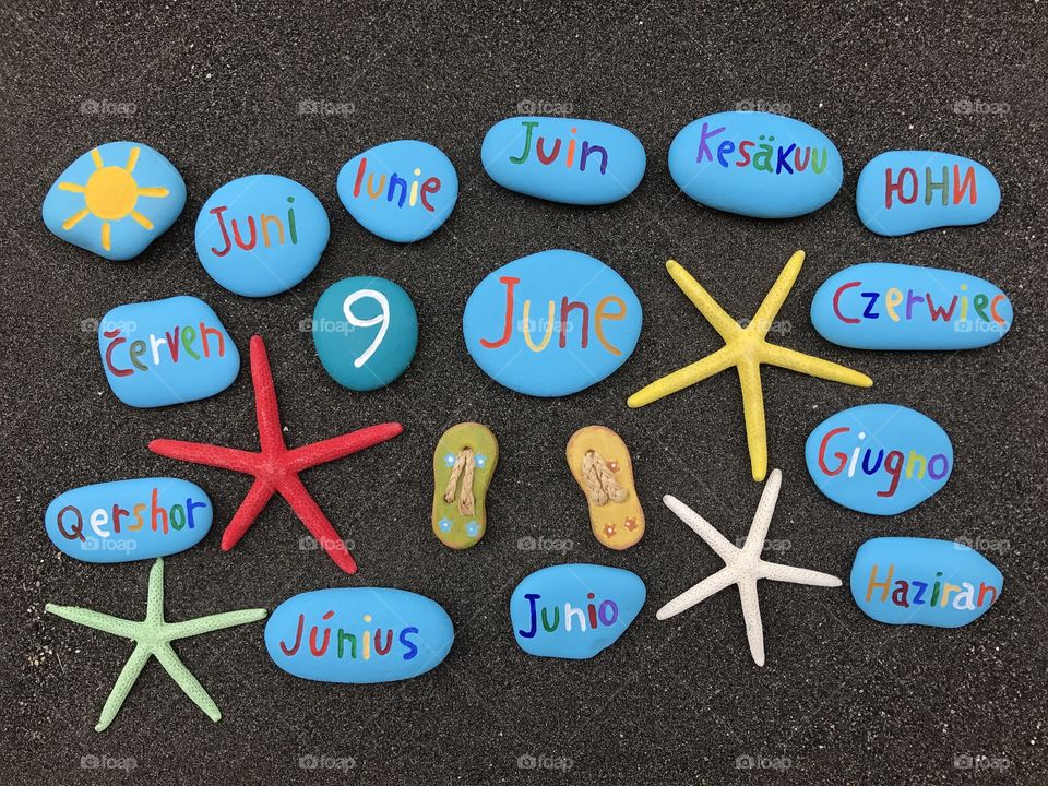 9 June, calendar date with multicolored stones and starfishes over the sand