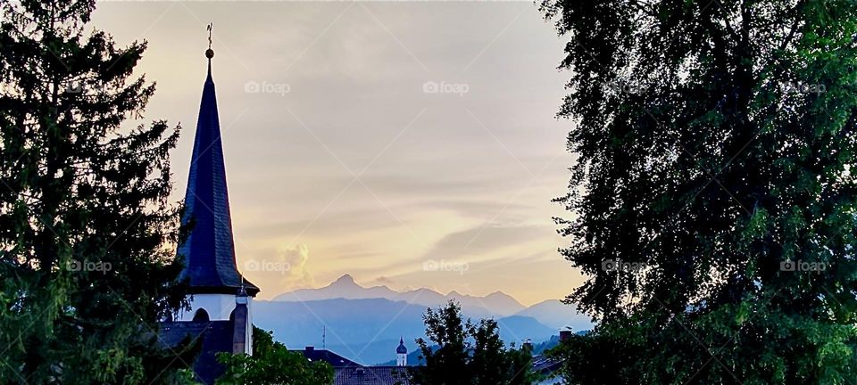 This beautiful forested landscape at sunset time comes to us from “Garmisch-Partenkirchen” in the Bavarian “Alps”. The silhouetted houses and trees in the foreground give way to sheer endless mountain ranges and glaciers. 2024. Hypnotic Productions