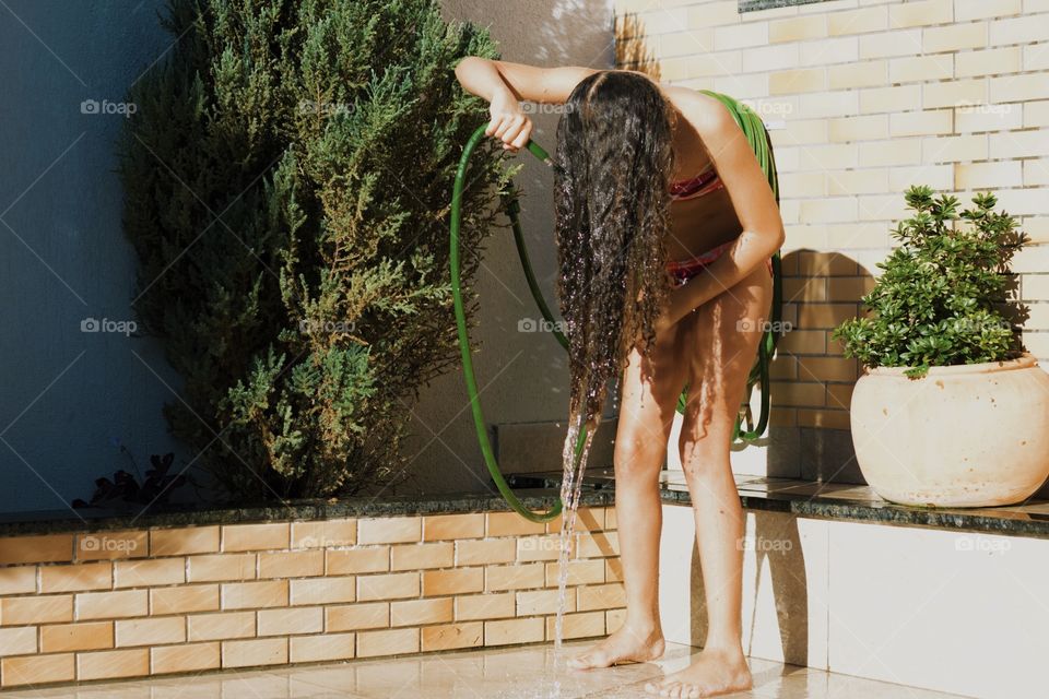 Child refreshing herself on the faucet in the garden.