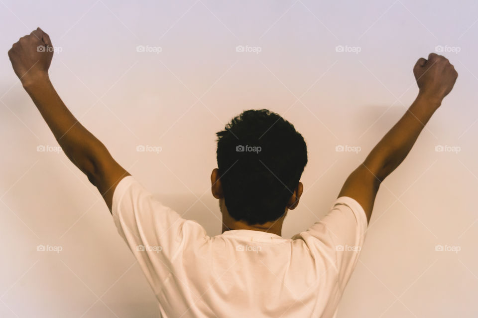 Studio shot of modern hipster young man with hands up, back view. isolated on white background