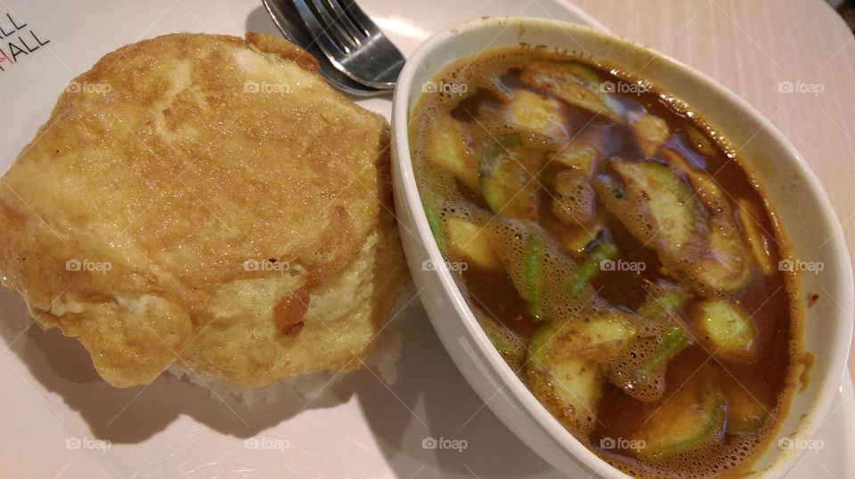 A dish of rice topping with Thai omelette served with Thai spicy curry southern style.