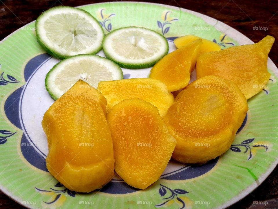 Juicy mango and leamon pices on a plat.