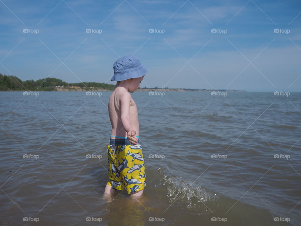 Toddler boy wading in the ocean.