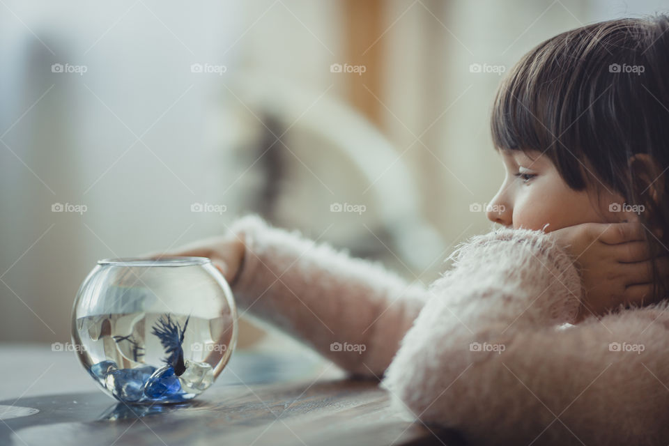 Girl with fish in round aquarium.