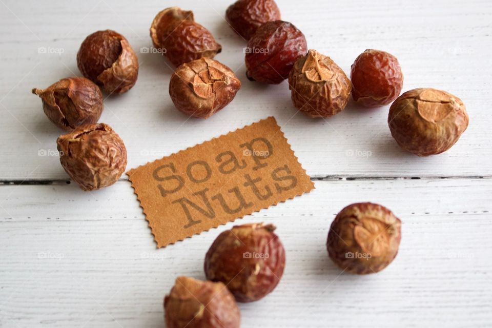 Soap nuts or soap berries on weathered white wooden background with identification placard in natural light