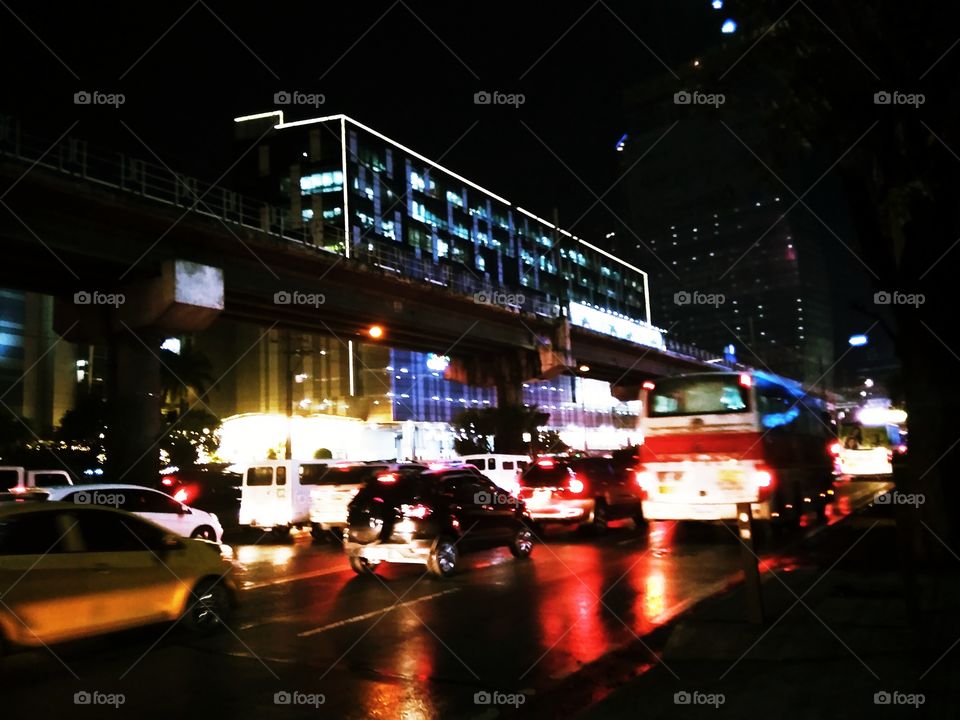 Night photography of the road in the busy city of Manila, Philippines. This picture is taken after the rain. the road is wet and the reflection from the road adds colors and beauty to it.