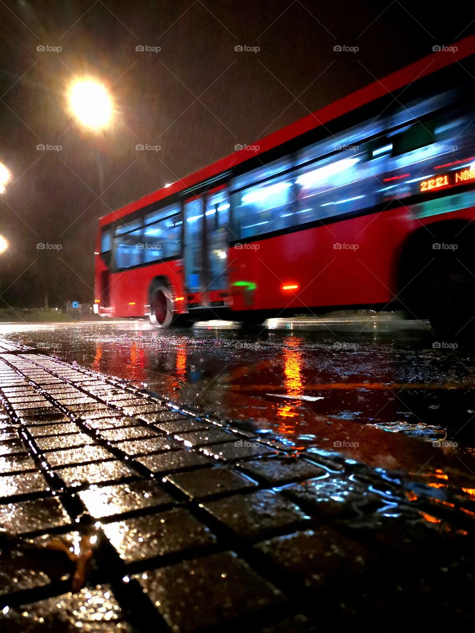 Autobús urbano en la novhe y lluvia. Reflejo