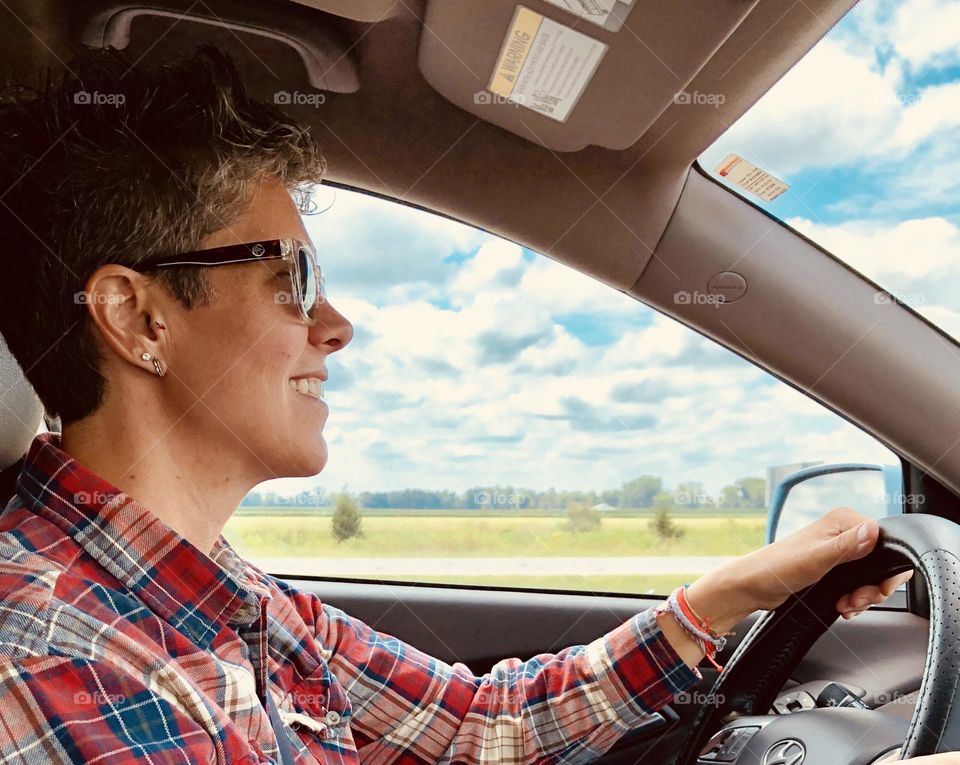 Woman driving on a road trip into the countryside, woman driving on a road trip, family takes a road trip, side profile of a woman driving, driving an SUV on a road trip