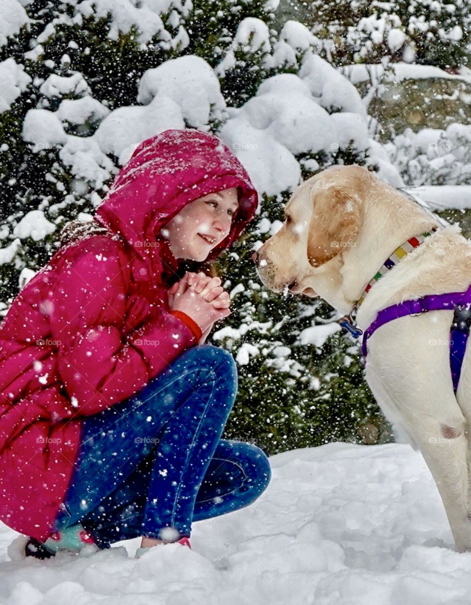 Snow falls on girl and her dog