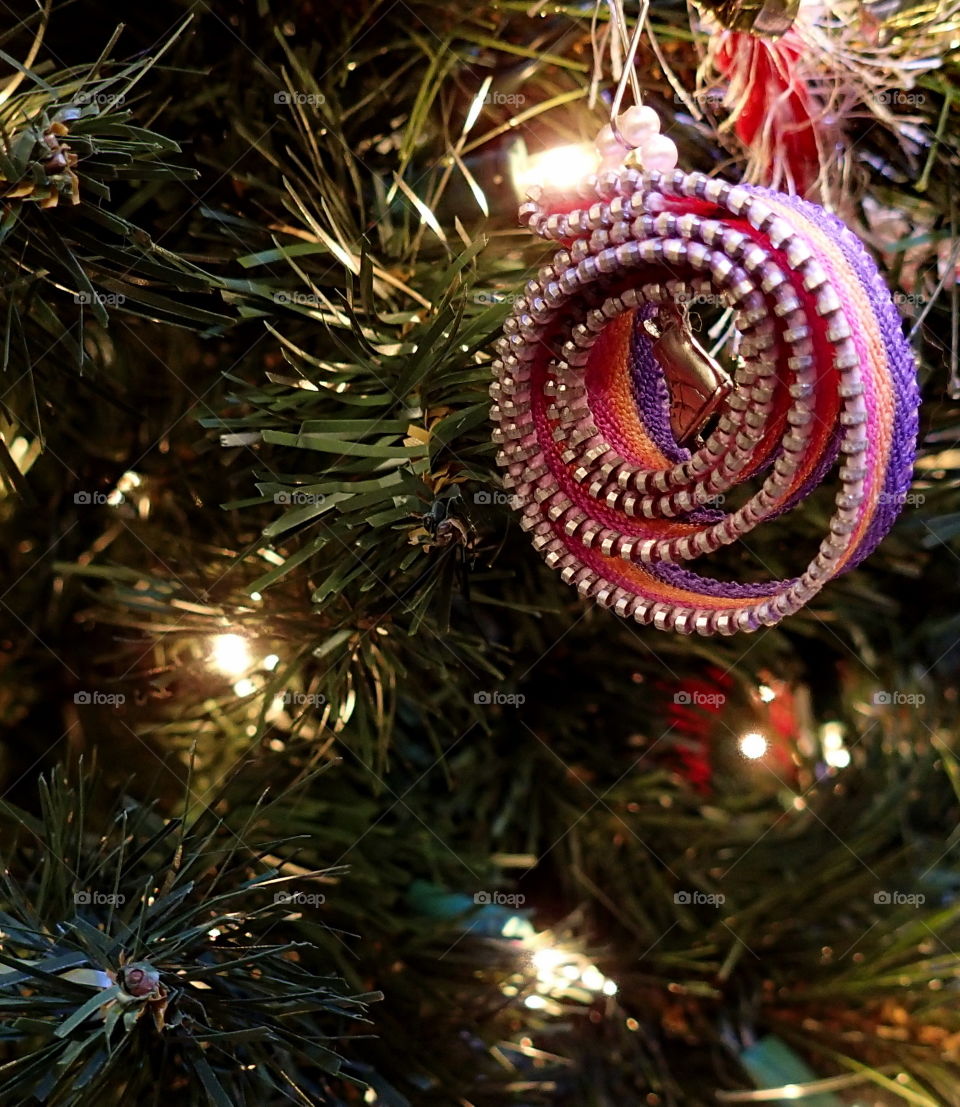 A curly and colored homemade Christmas ornament hangs from the tree. 