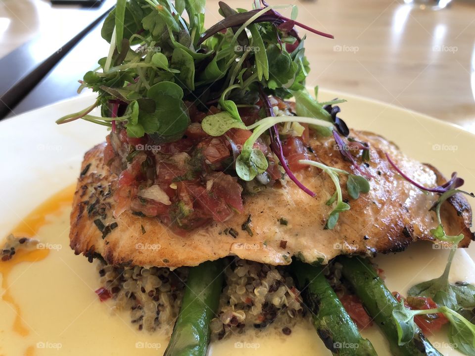 Wild Salmon pan fried crust with moist texture topped with salsa and arugula salad over quinoa and asparagus spears