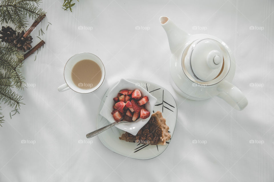 Tea, strawberries and pecan pie beside  a teapot in a festive flat lay