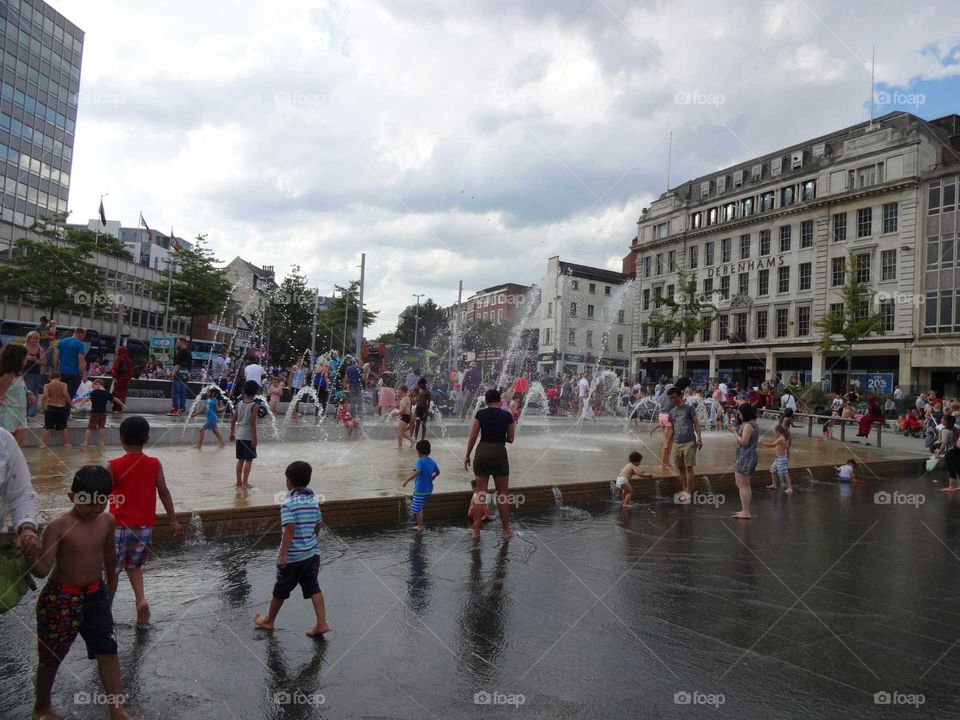 City life. People cooling off in the fountains at Old Market Square in Nottingham, England