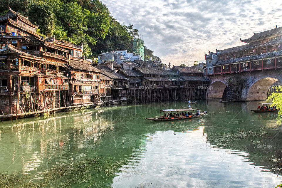 A Touristic Longtail Boat Floating Through The Ancient City Of Fenghuang, China