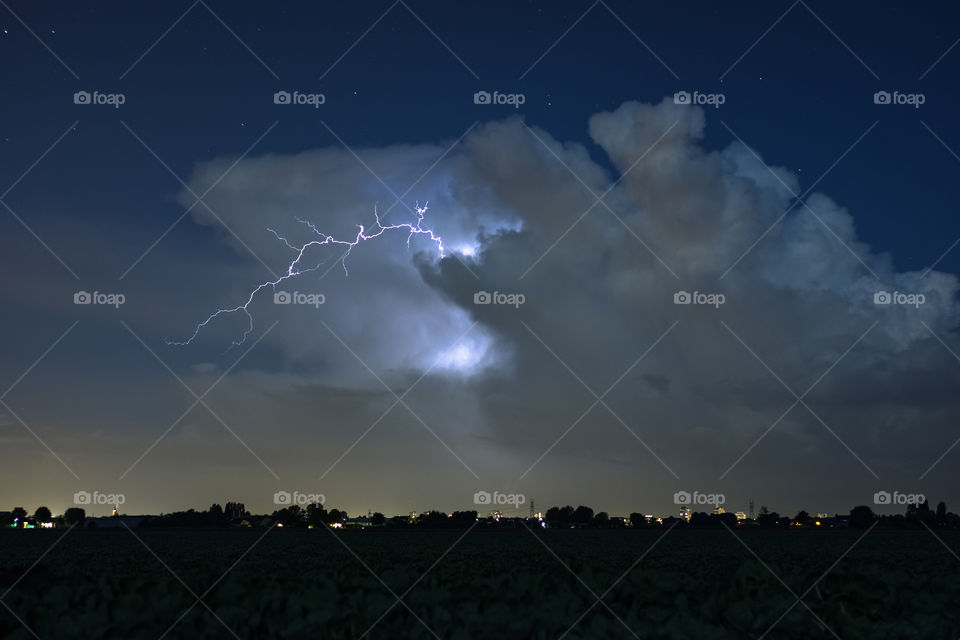 A lightning bolt jumps out of the anvil of a thunderstorm. Photographed in the western part of the Netherlands, close to the cities of The Hague and Rotterdam.
