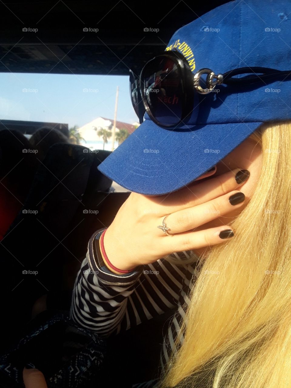 Sister wearing a black and white striped dress and a blue Virginia beach baseball hat, blocking the sun as well as hiding her face.