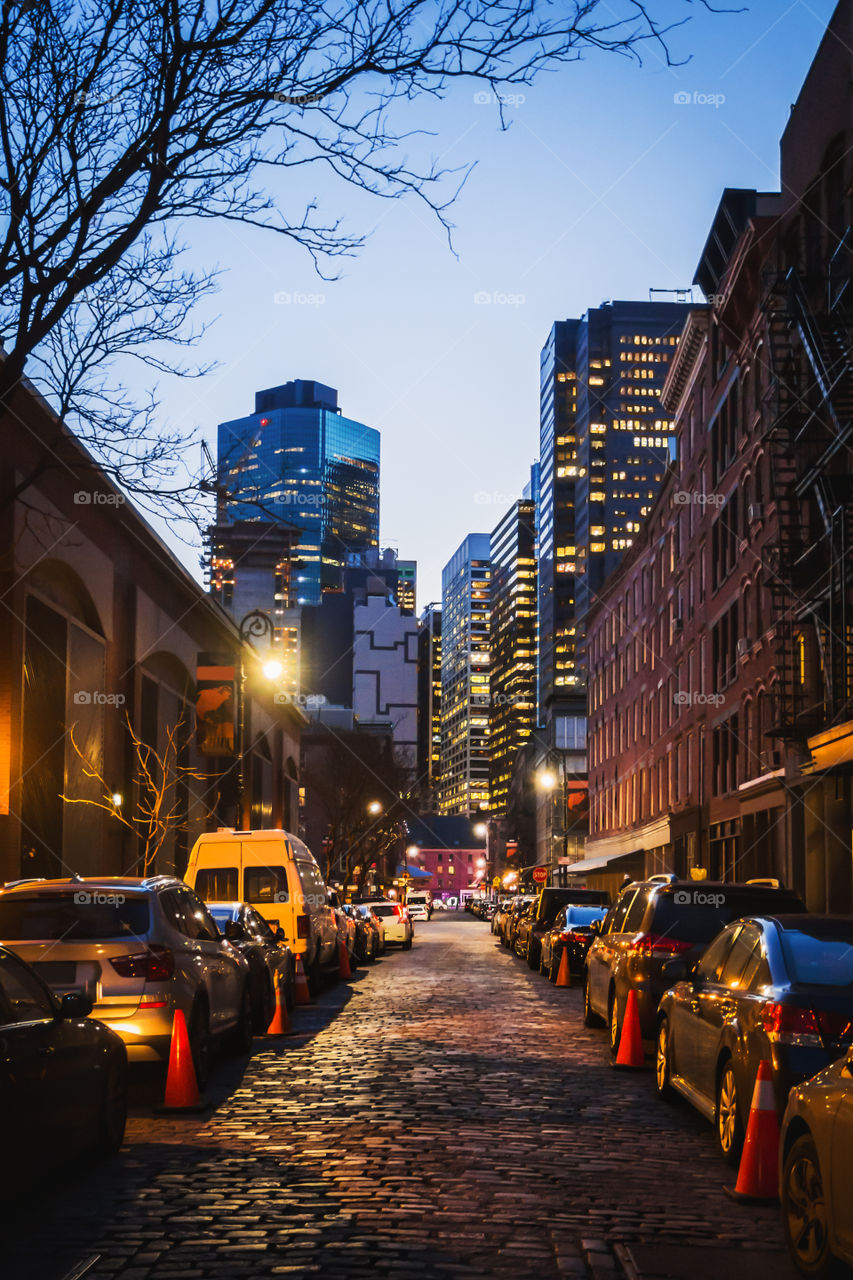 Night cityscape colored of an old street of New York to the modern office buildings in background 