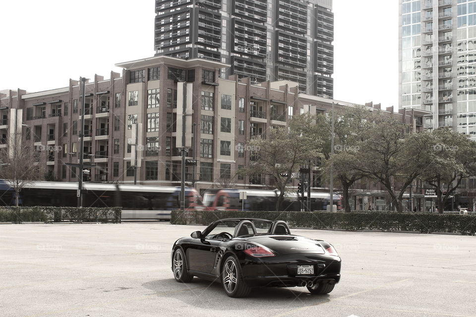 Black porsche convertible in city with moving train, unsaturated