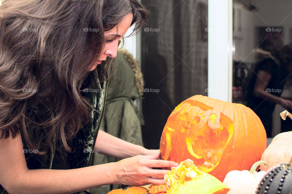 Woman carving pumpkins for Halloween night at home closeup of cute dog jack o’lantern