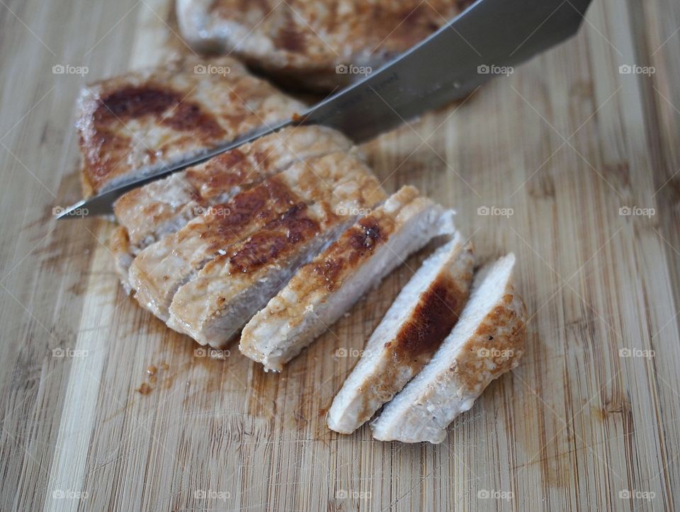 Freshly cooked pork being sliced of not pieces for use with accompanying dishes. 
