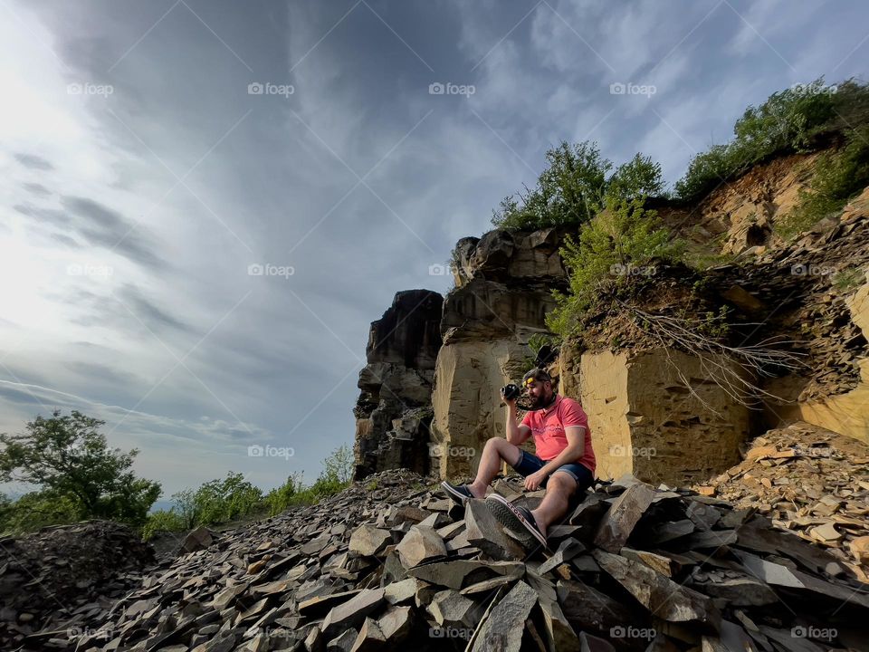 A man with the camera in hand near the rocks